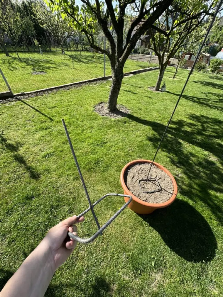 Malý stabilizátor v ruke, v pozadí tyč v kvetináči